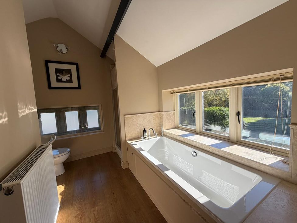 A bathroom with a bathtub and a toilet at Honey Pot Cottage near Harrogate