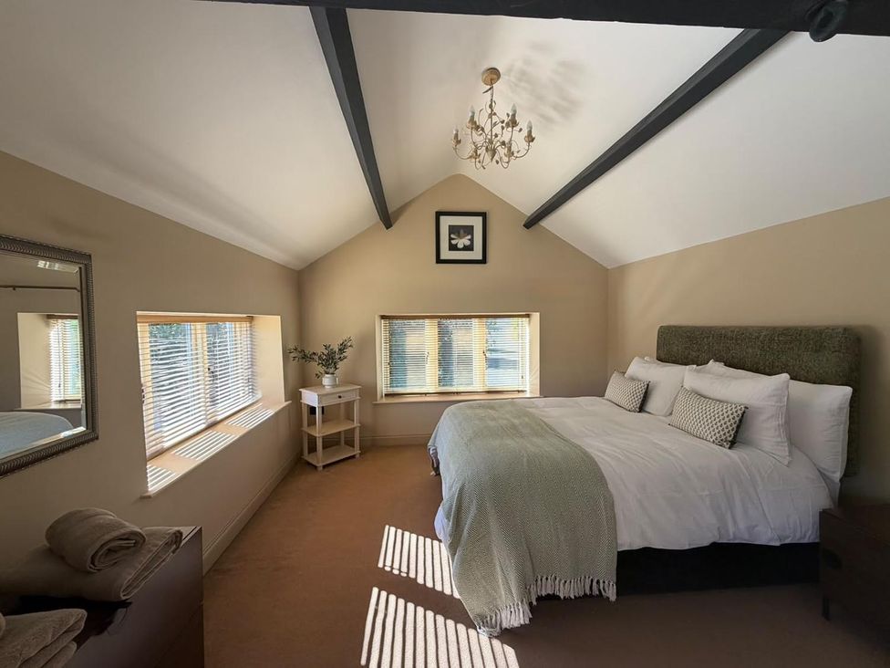 A bedroom with a bed and windows at Honey Pot Cottage near Harrogate