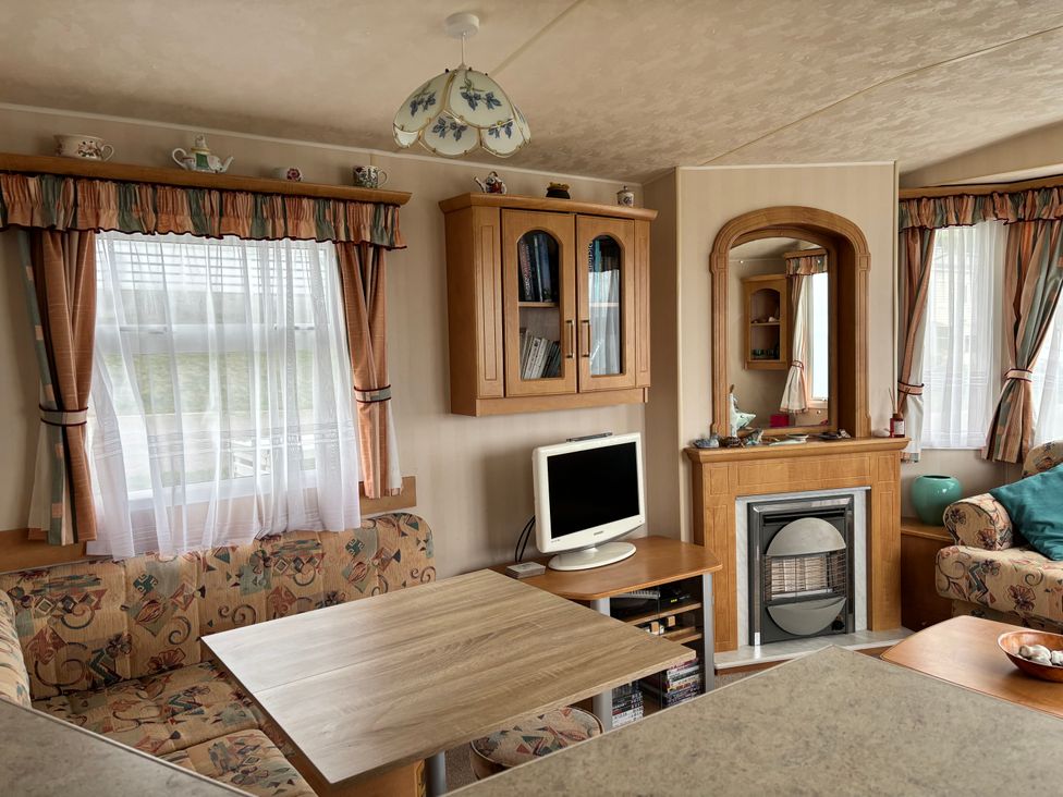 A living room with a sofa, dining table, and TV at Beer Head Caravan Park B68 in Seaton
