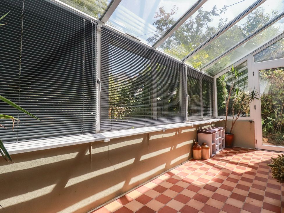 A conservatory with plants and shelves at 1 Grenville Road, Truro