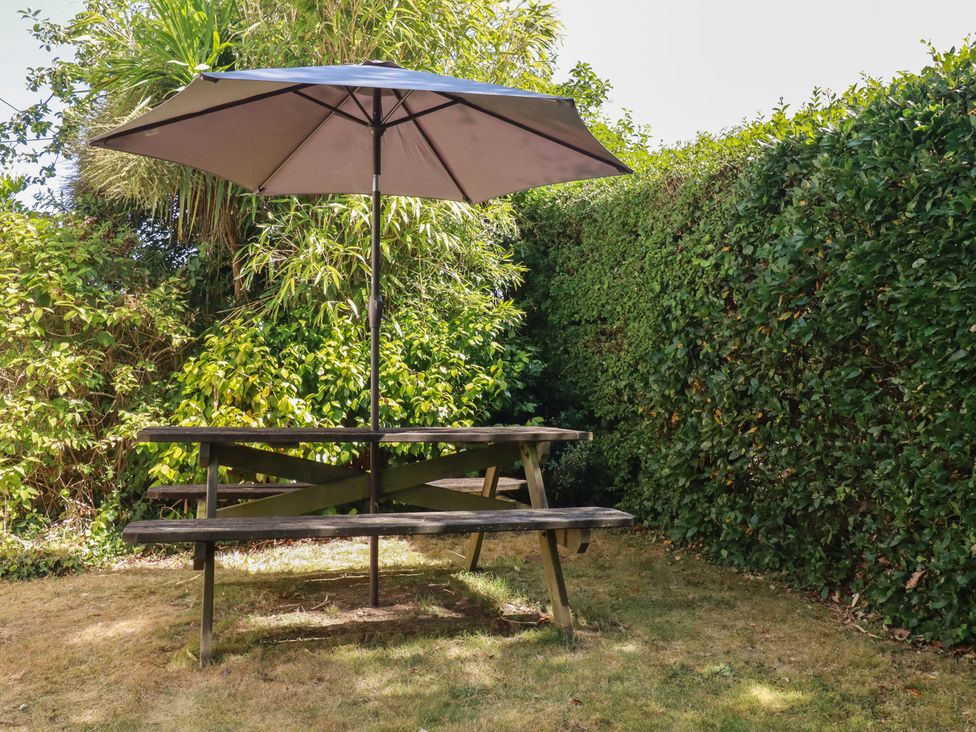 A table with an umbrella in a garden at 1 Grenville Road Truro