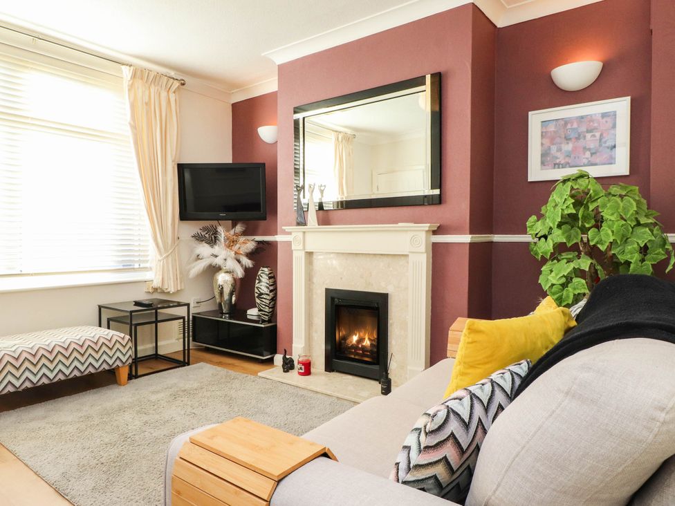 A living room with a fireplace and sofa at Carol Ann Llandudno