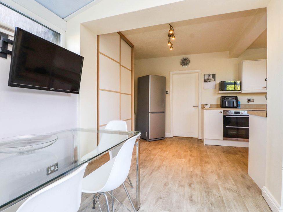 A kitchen with a dining table and appliances at Carol Ann Llandudno