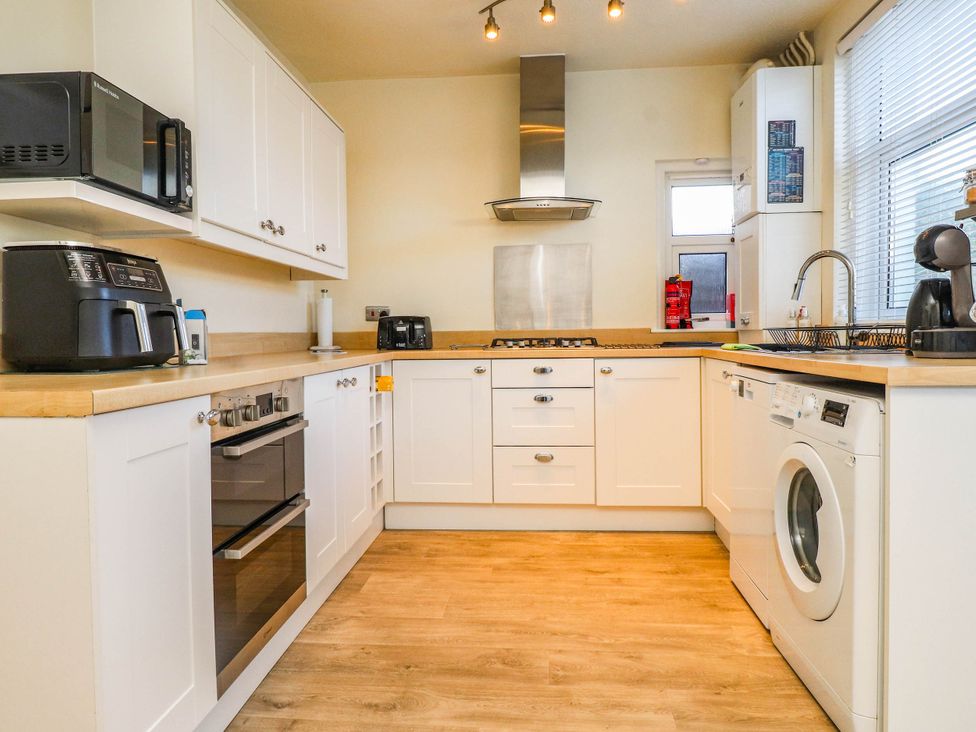A kitchen with appliances and cabinets at Carol Ann Llandudno