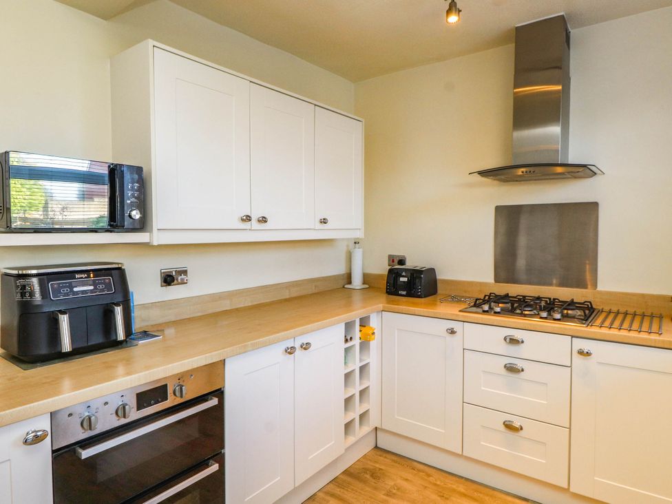 A kitchen with an air fryer, microwave, oven, and cooktop at Carol Ann Llandudno