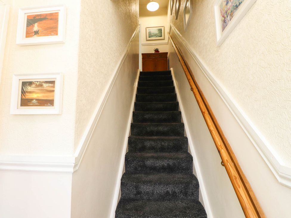 A staircase leading up with framed pictures on the walls at Carol Ann Llandudno