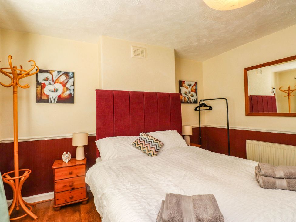 A bedroom with a bed and lamp at Carol Ann Llandudno