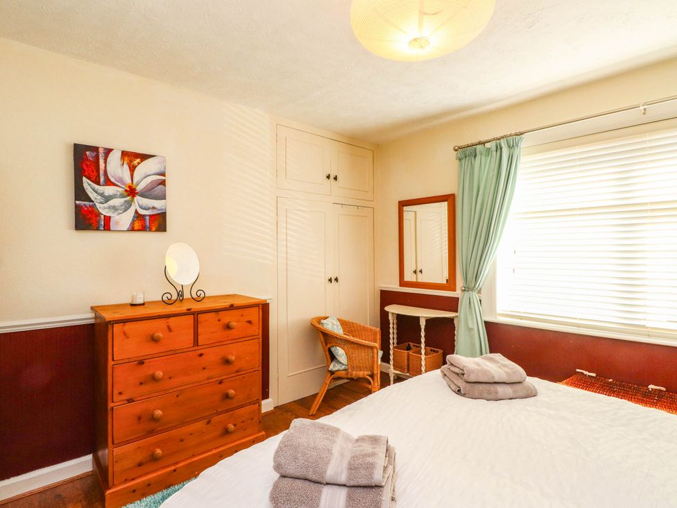 A bedroom with a bed, dresser, and mirror at Carol Ann Llandudno