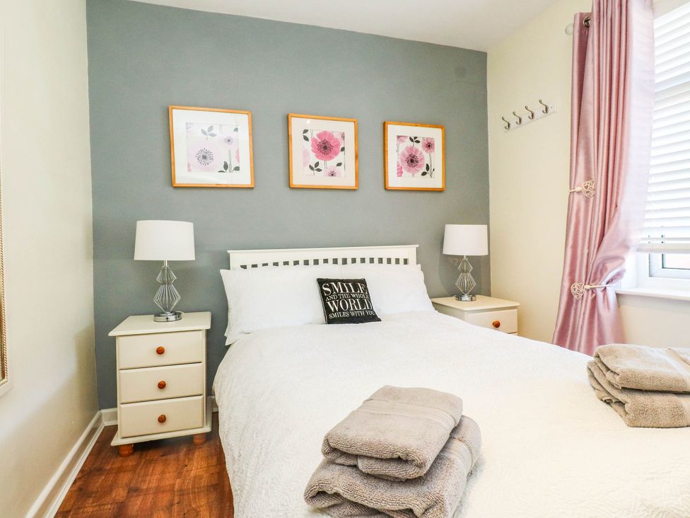 A bedroom with a bed and bedside tables at Carol Ann Llandudno