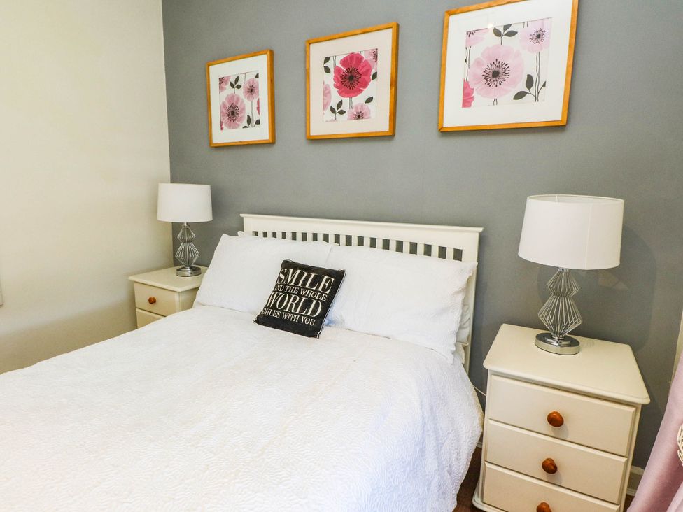 A bedroom with a bed and nightstands at Carol Ann Llandudno