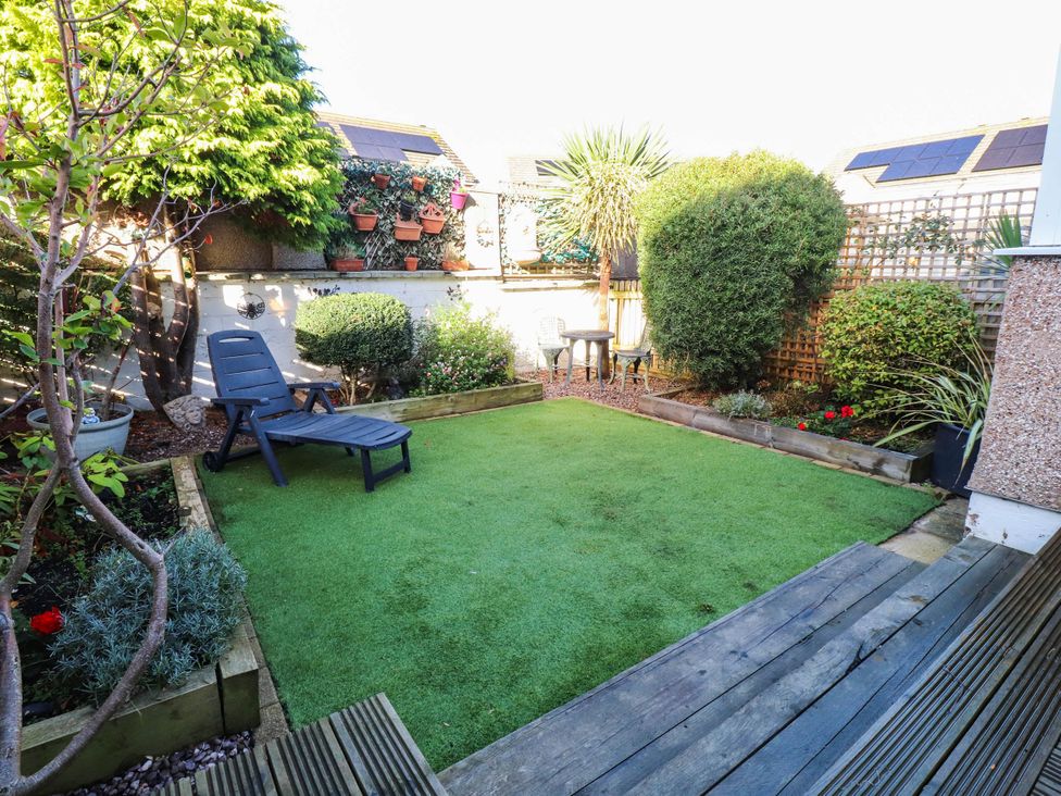 A garden with grass, plants, and a chair at Carol Ann Llandudno