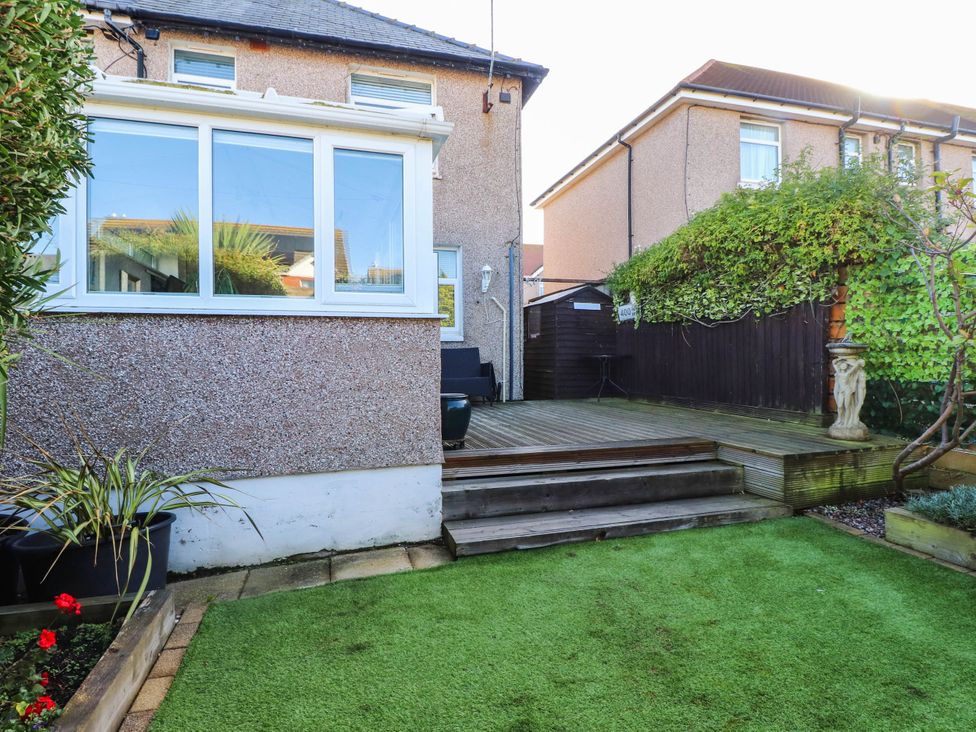 A garden with decking and plant pots at Carol Ann Llandudno
