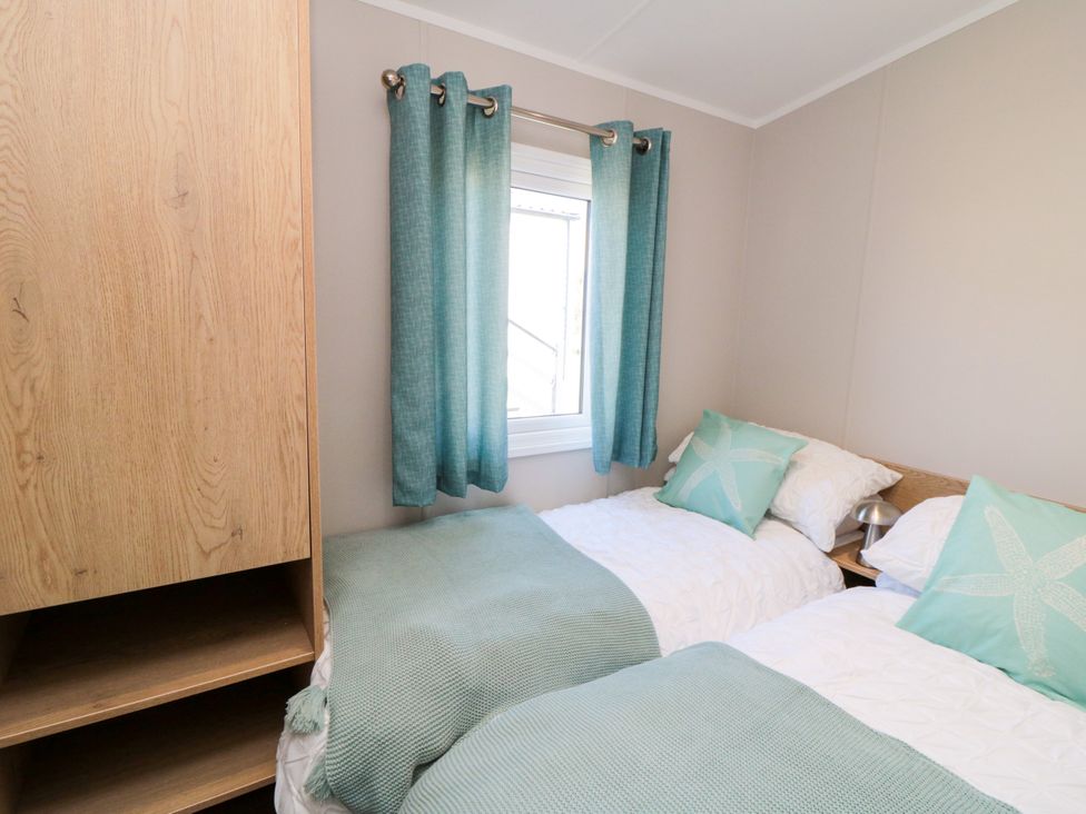 A bedroom with two beds and a wardrobe at 5 Rowen Court in Scarborough