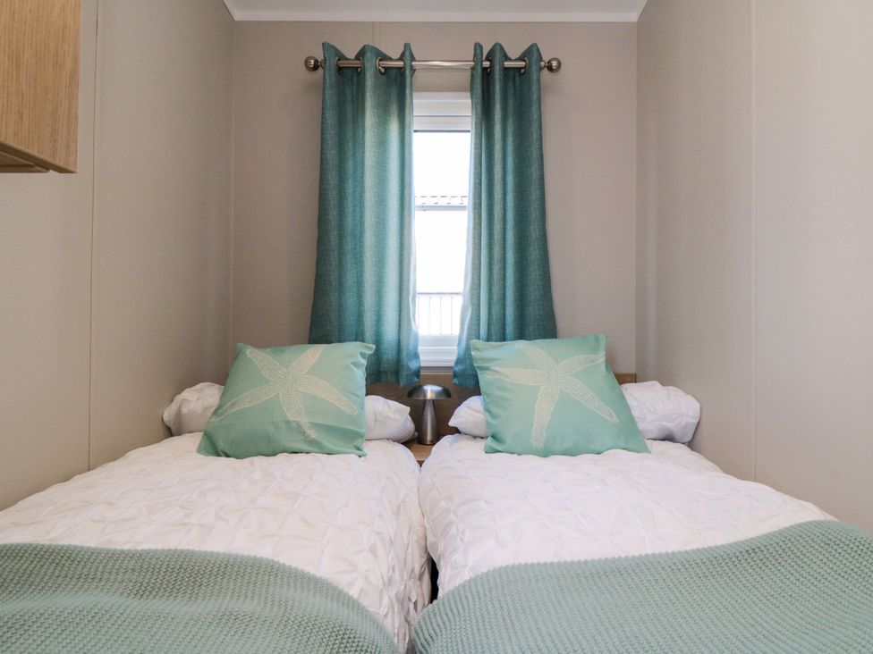 A bedroom with two beds and curtains at 5 Rowen Court in Scarborough