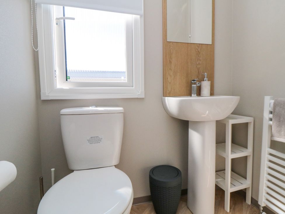 A bathroom with a toilet, sink, and mirror at 5 Rowen Court in Scarborough