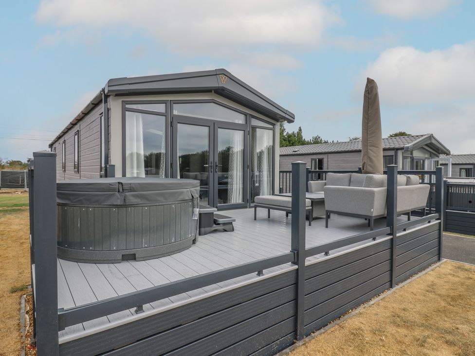 An outdoor patio with a hot tub and seating at Lodge 1 in St. Osyth
