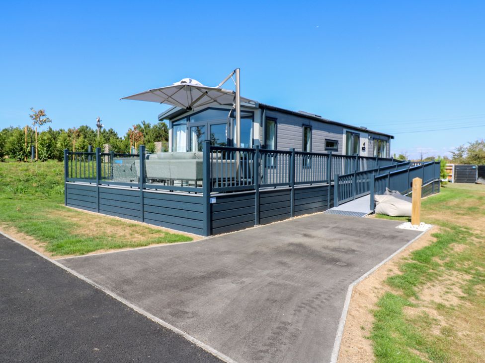 An outdoor seating area with a parasol and decking at Lakewood Plot 1 in St. Osyth