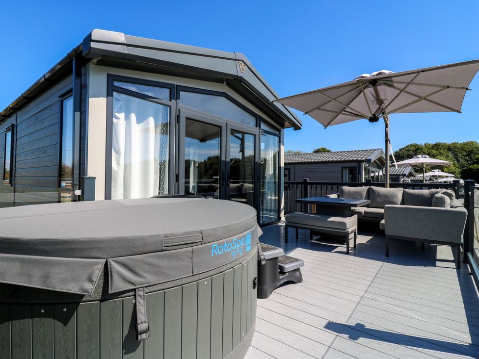 An outdoor seating area with a hot tub and umbrella at Lakewood Plot 1 St. Osyth