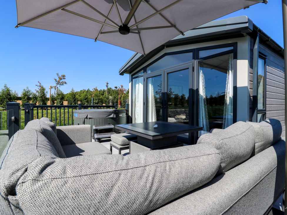 An outdoor area with a sofa and table under an umbrella at Lakewood Plot 1 St. Osyth