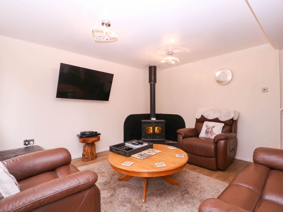 A living room with a television, sofa, and wood stove at The Warm Hearth in Hereford