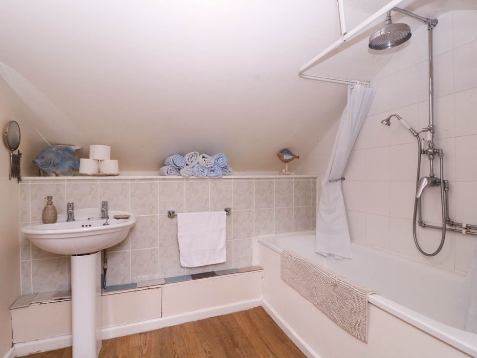 A bathroom featuring a bathtub, wash basin, and towels at The Warm Hearth in Hereford