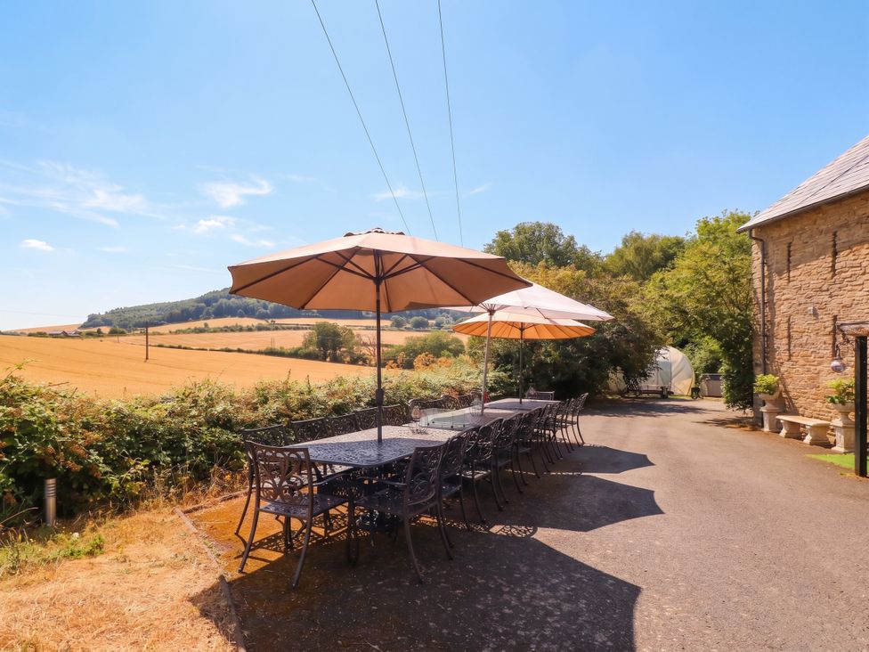 An outdoor area with a table and chairs under umbrellas at The Warm Hearth in Hereford