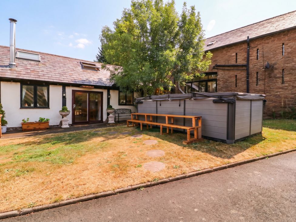 An outdoor area with a hot tub and a wooden bench at The Warm Hearth in Hereford