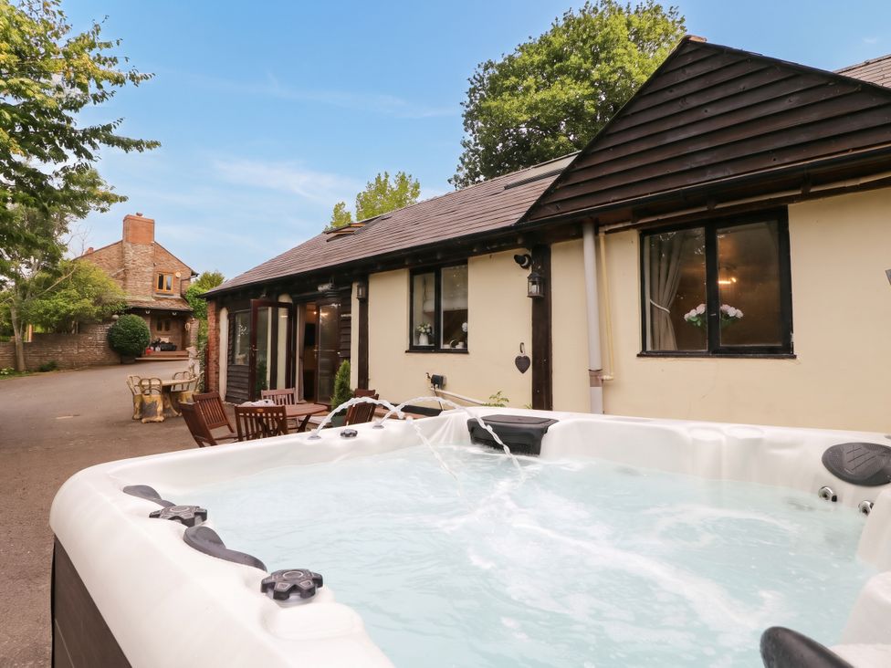 An outdoor area with a hot tub and a house at The Warm Hearth in Hereford