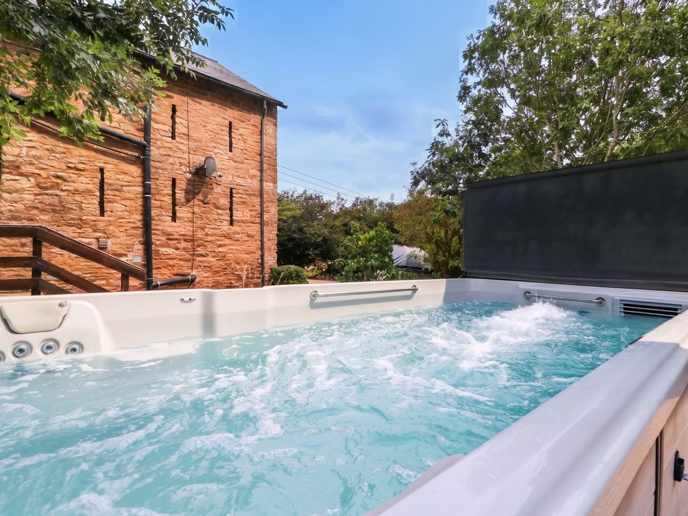 A hot tub with water and a brick wall at The Warm Hearth in Hereford