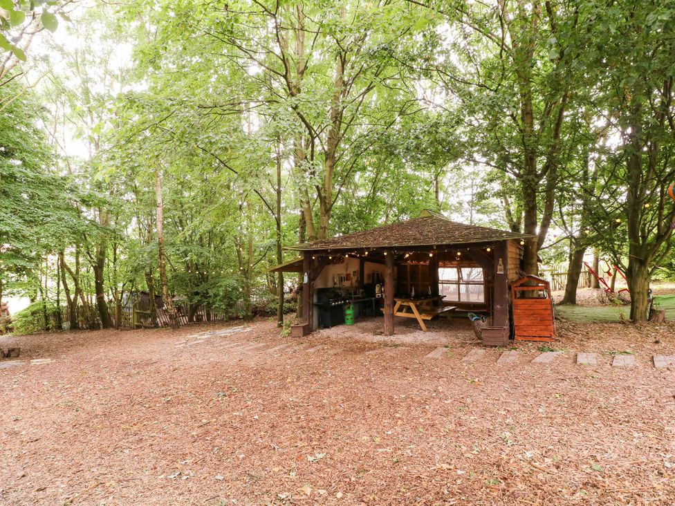 An outdoor structure with a table and grill in a garden at The Warm Hearth in Hereford
