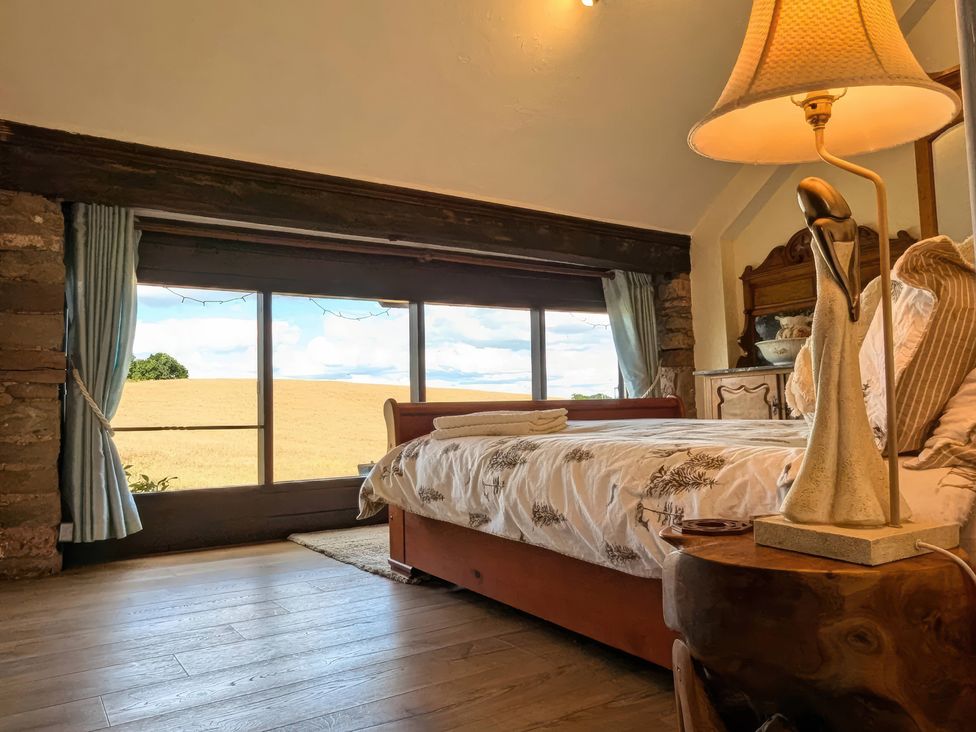 A bedroom with a bed and a window overlooking fields at The Warm Hearth: 15 Acre Countryside Estate Hereford