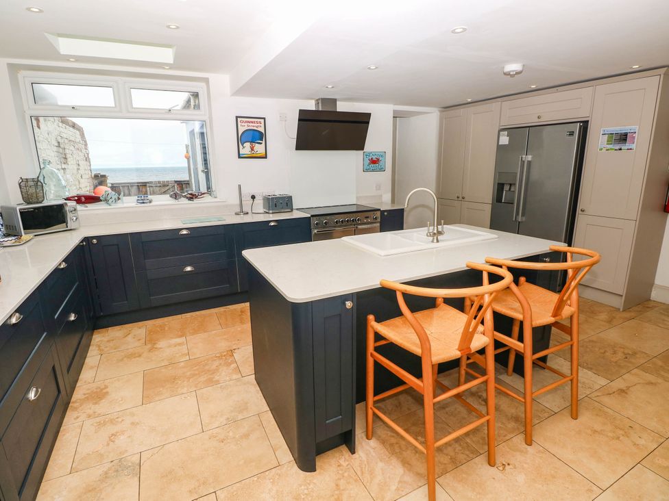 A kitchen with modern appliances and bar stools at Y Glyn in Borth