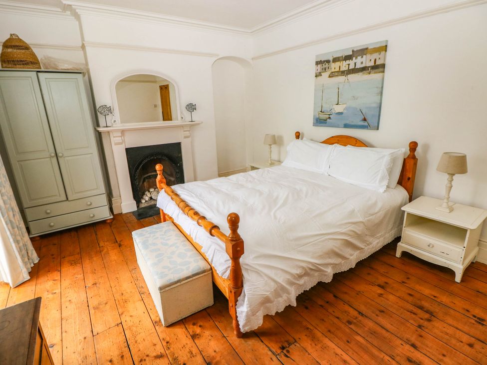 A bedroom with a bed, wardrobe, and fireplace at Y Glyn in Borth