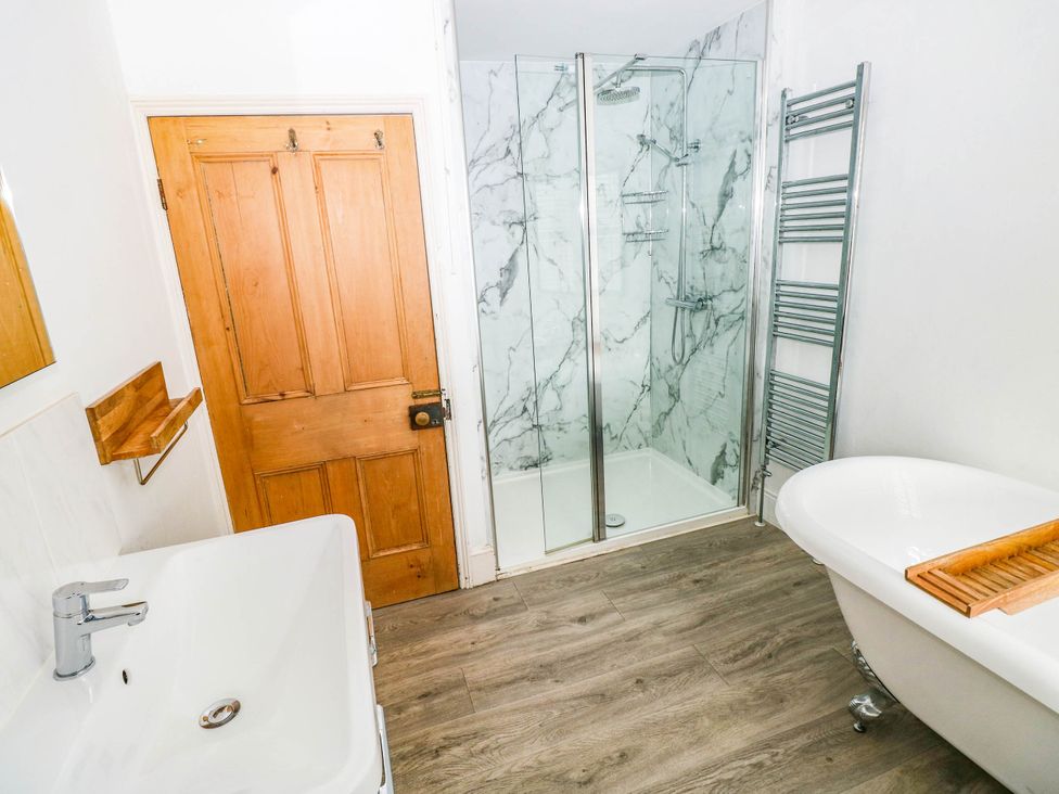 A bathroom with a bathtub, shower, sink, and towel radiator at Y Glyn in Borth