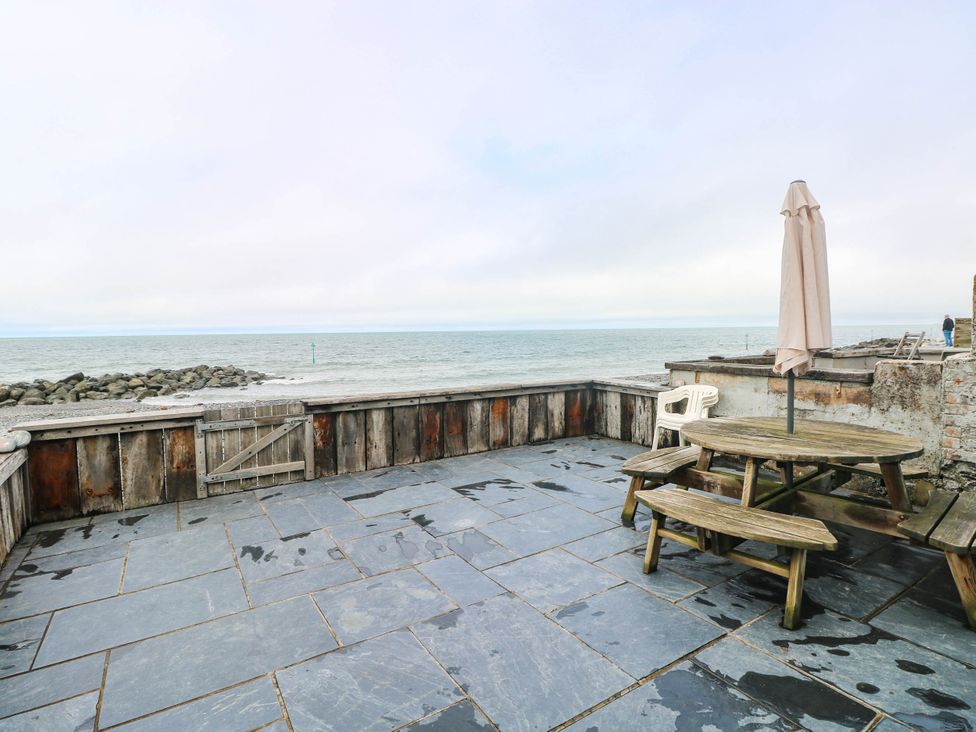 An outdoor area with a table and benches overlooking the sea at Y Glyn, Borth