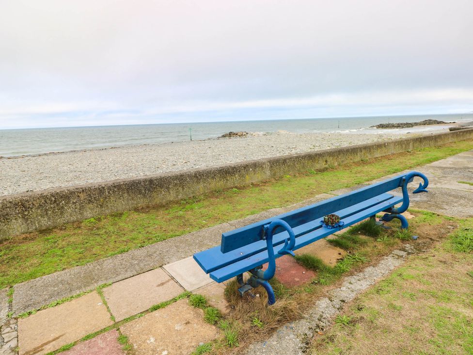 A blue bench along a pathway near the seaside at Y Glyn Borth