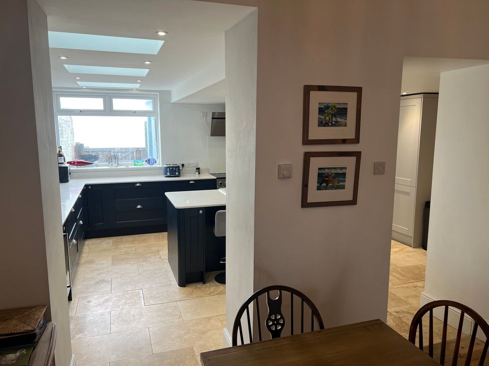 A kitchen with cabinets, countertop, and a dining area at Y Glyn in Borth