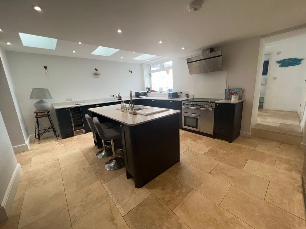 A kitchen with an island and stools at Y Glyn in Borth
