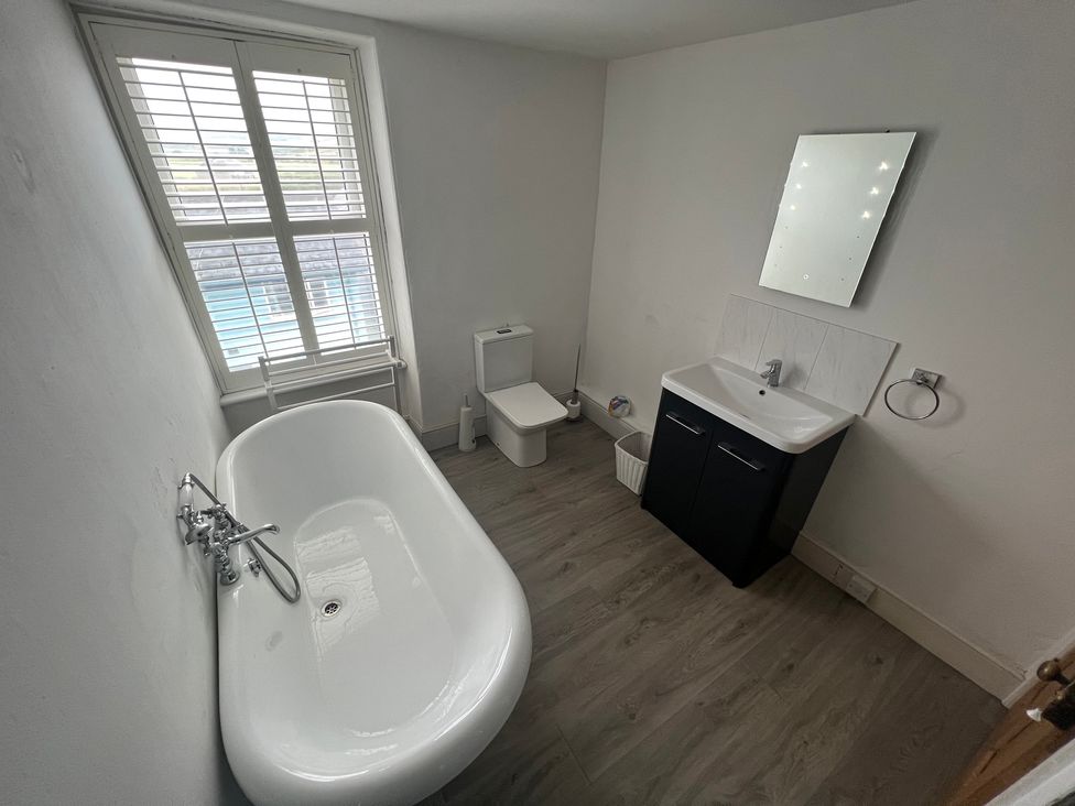 A bathroom with a bathtub, toilet, and sink at Y Glyn in Borth