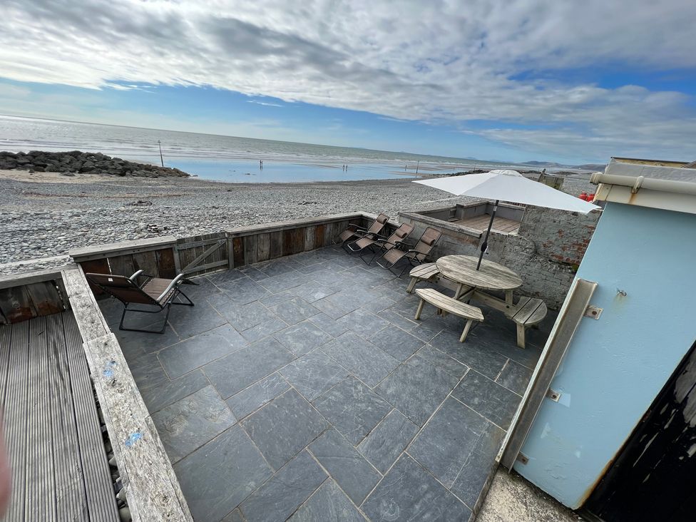 An outdoor seating area with table and chairs overlooking the beach at Y Glyn Borth