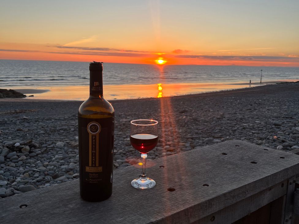A bottle of wine and a glass on a wooden surface at Y Glyn in Borth