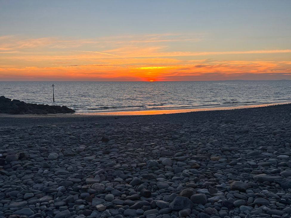 A sunset over the ocean with pebbles in the foreground at a beach