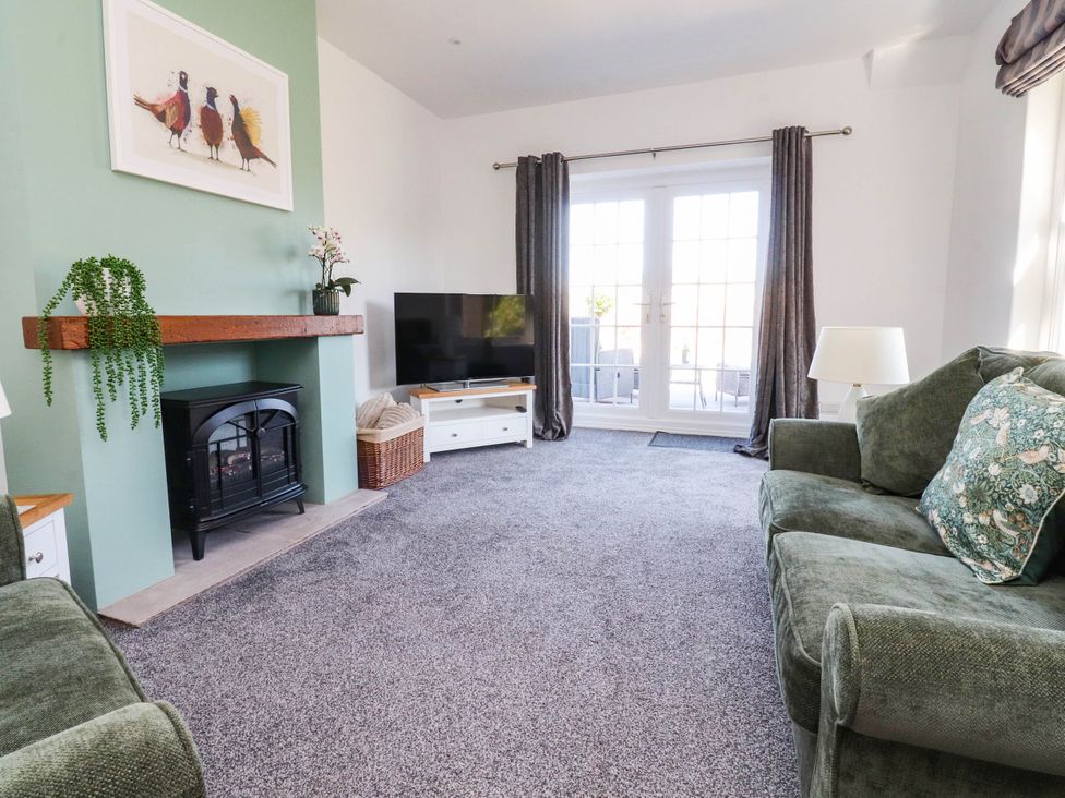 A living room with a fireplace and tv at The Swallows near Glasson