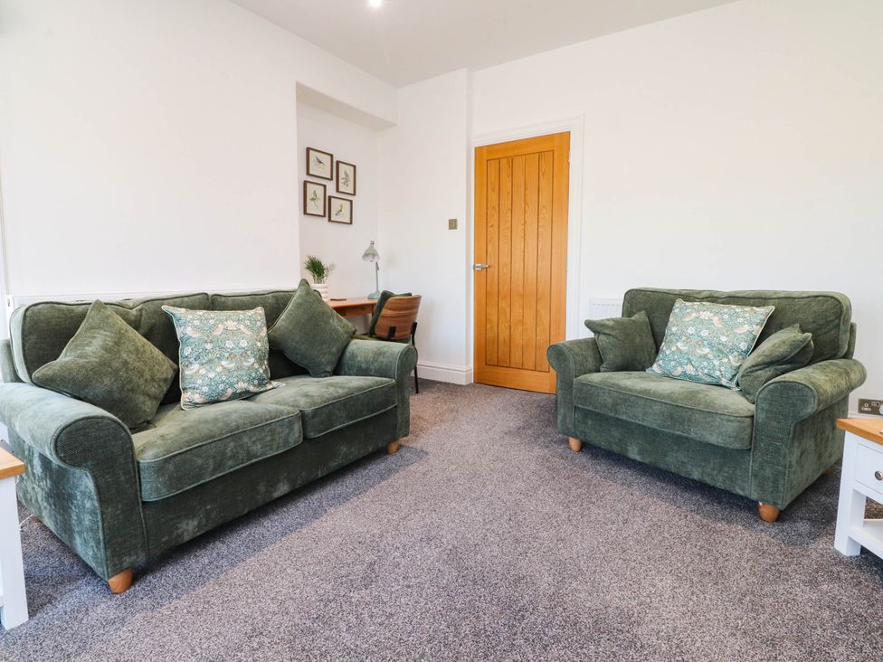 A living room with two sofas and a desk at The Swallows near Glasson