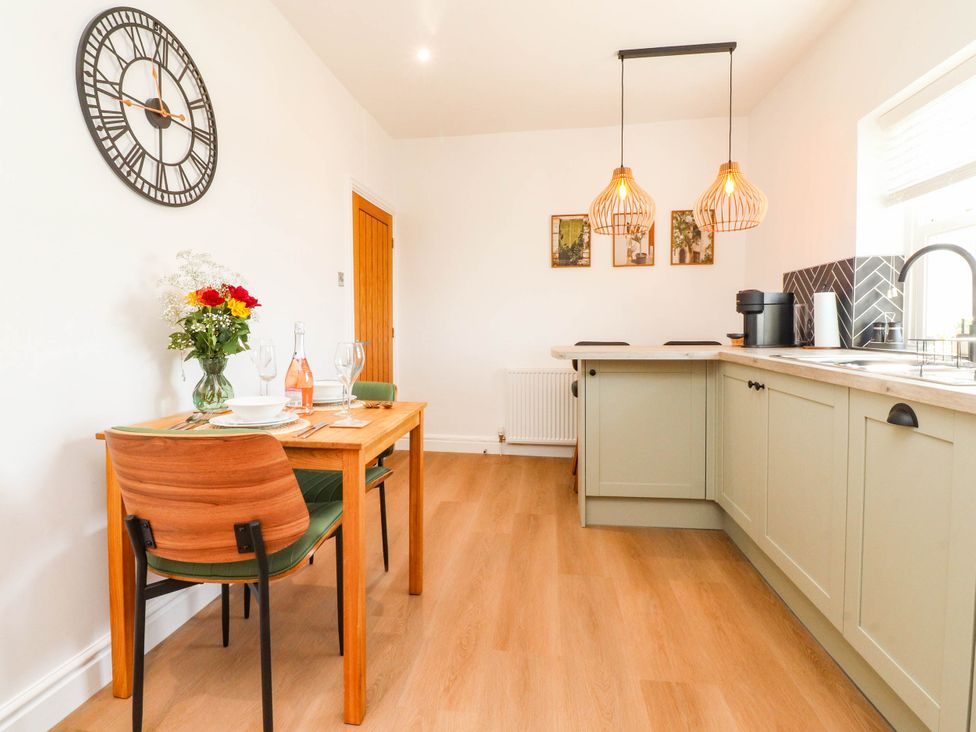 A dining room with a table and flowers at The Swallows near Glasson