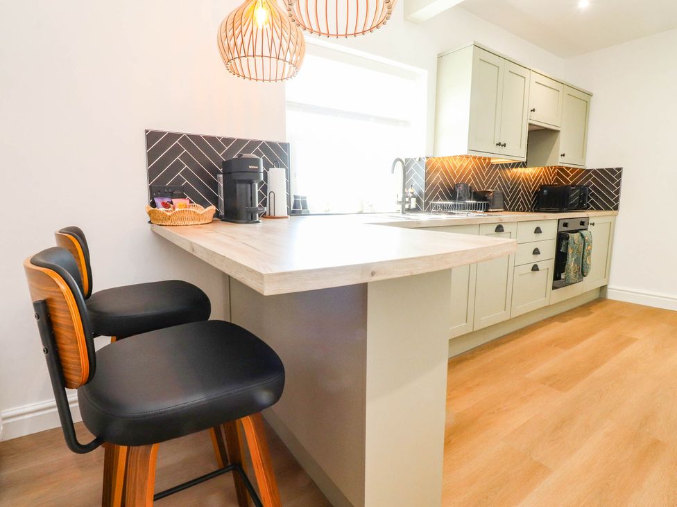 A kitchen with a counter and stools at The Swallows near Glasson