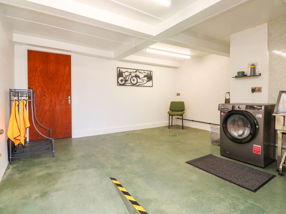A laundry room with a washing machine and a chair at The Swallows near Glasson