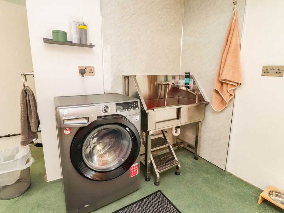 A utility room with a washing machine and sink at The Swallows near Glasson
