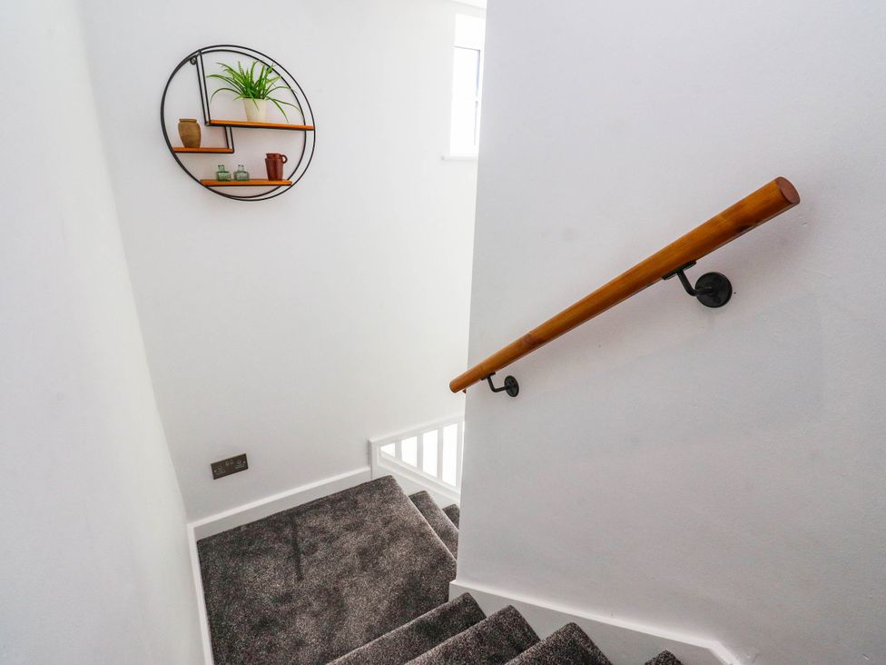 A staircase with a handrail and a wall shelf at The Swallows near Glasson