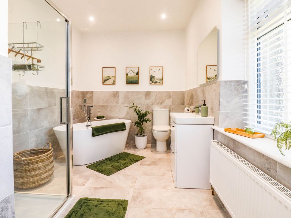 A bathroom with a bathtub, shower, sink, and toilet at The Swallows near Glasson